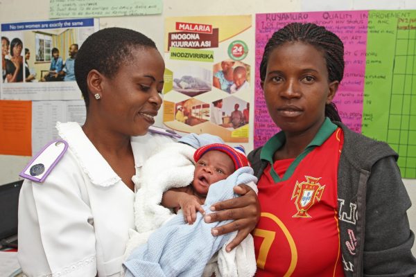 Zimbabwean midwife holding a woman's baby.