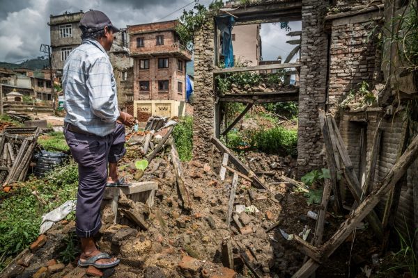 Man surveying a destroyed dwelling in Nepal.