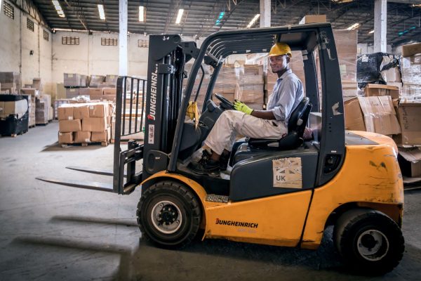 Warehouse worker riding a forklift.